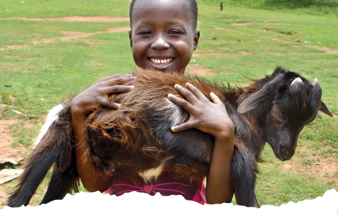 When you buy a goat for a family in Africa real families benefit. Image shows African girl holding a goat.