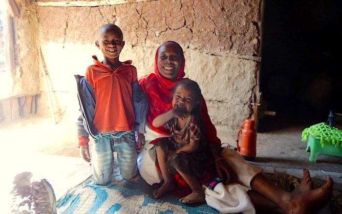 Kelsuma sits with her daughter and son in their modest home