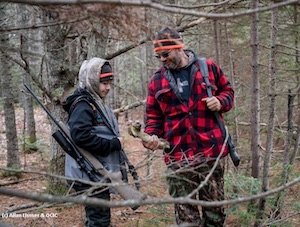 Piel and his father Ernie standing in a forest inspecting a bone