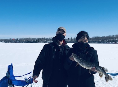 Community member holding a fish on a frozen lake