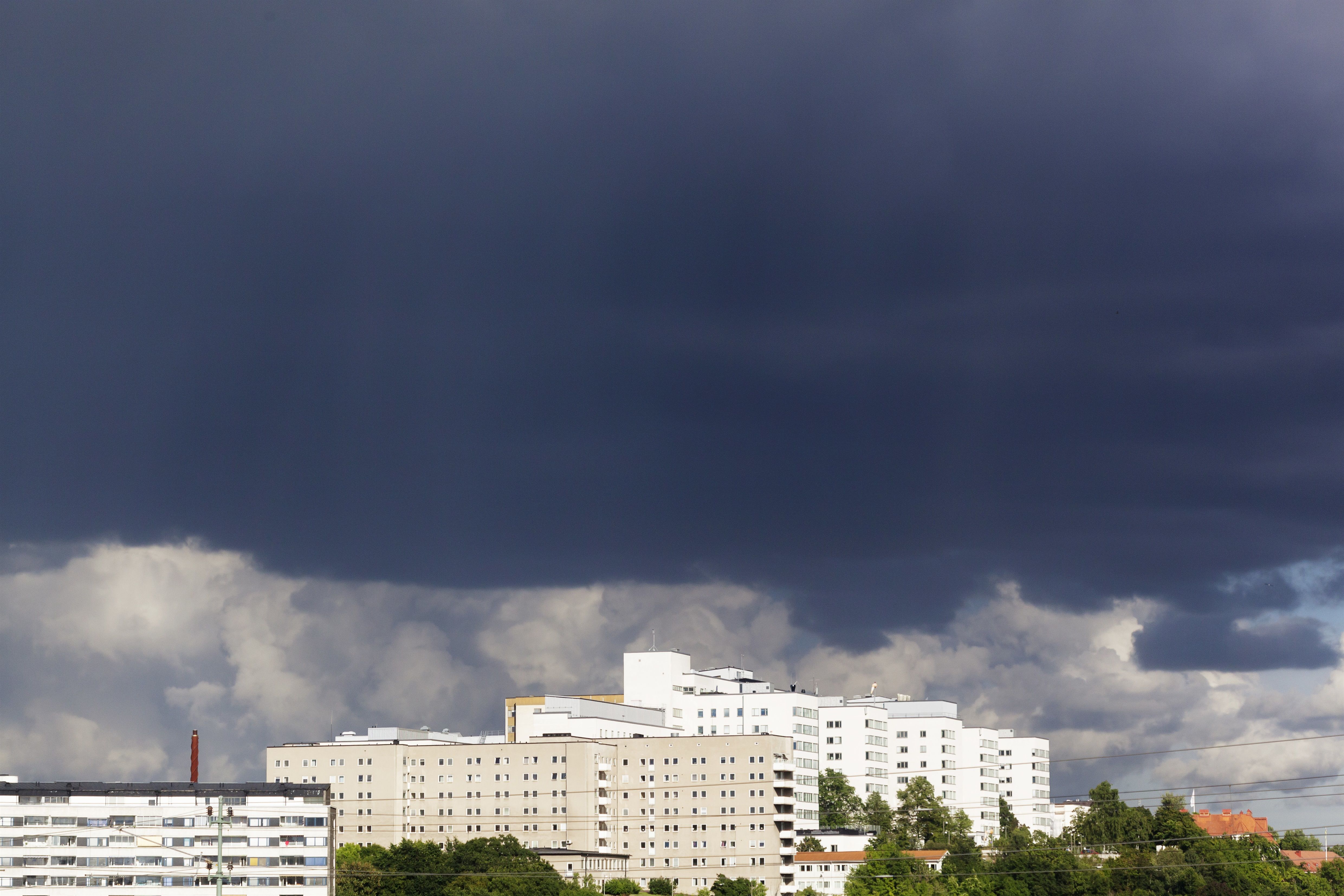 Tunga regnmoln över vita höghus.