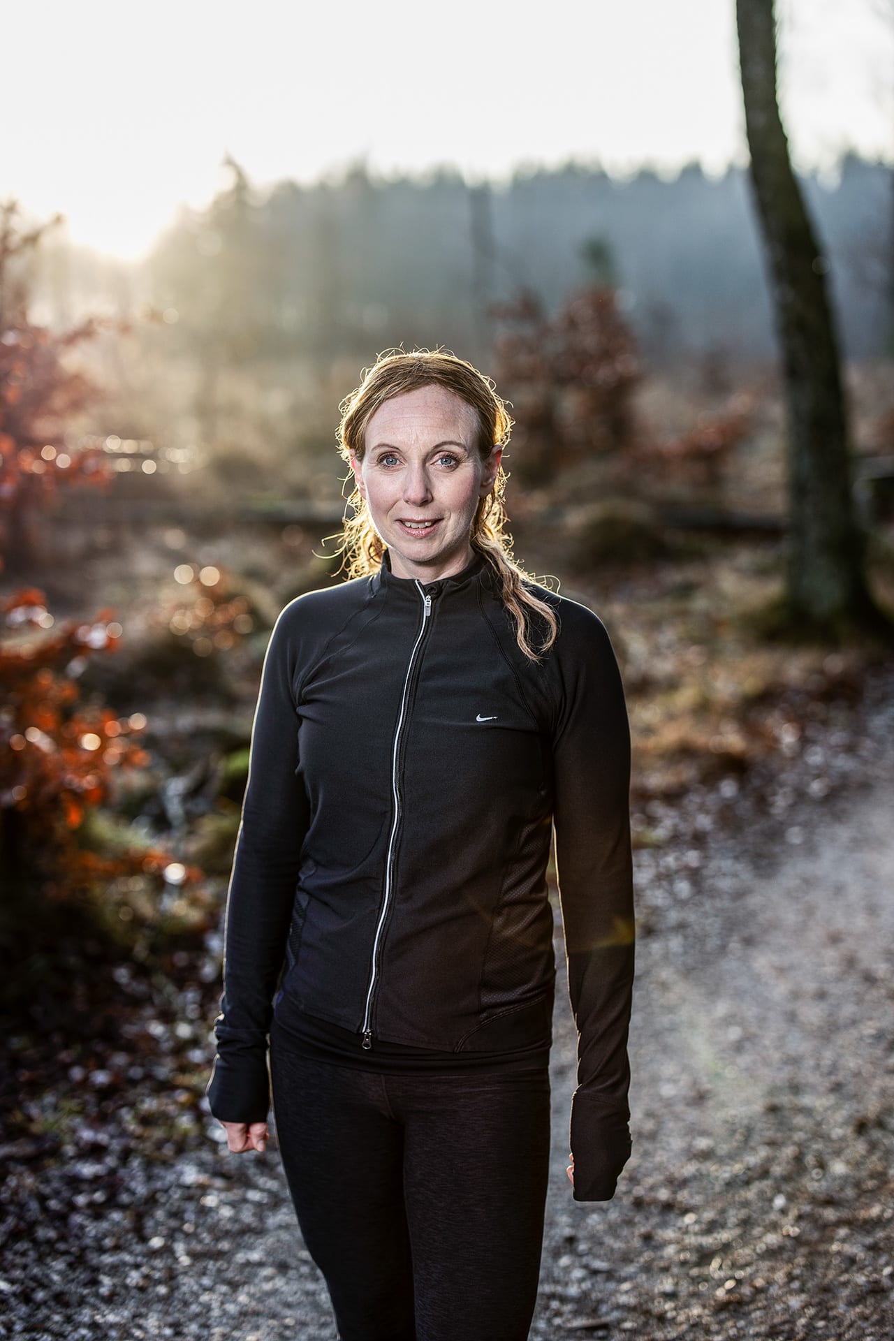 Frida Eek står i ett motionsspår i skogen. Klädd i träningskläder.