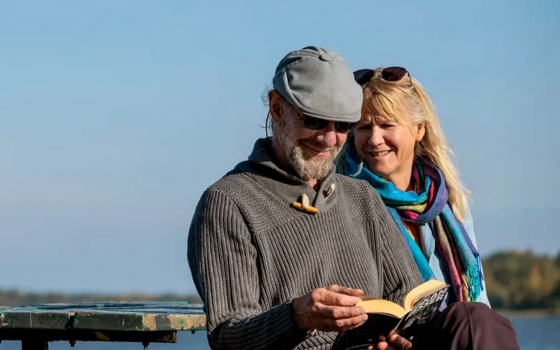 Äldre par sitter på en bänk i solen