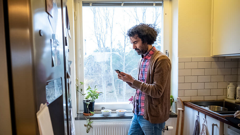 Man står i ett kök med telefon