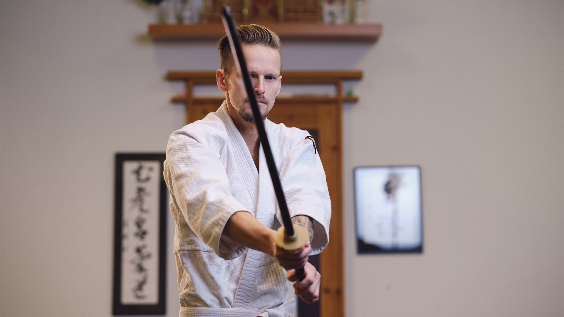 Erik står i en kampsportslokal med ett svärd.