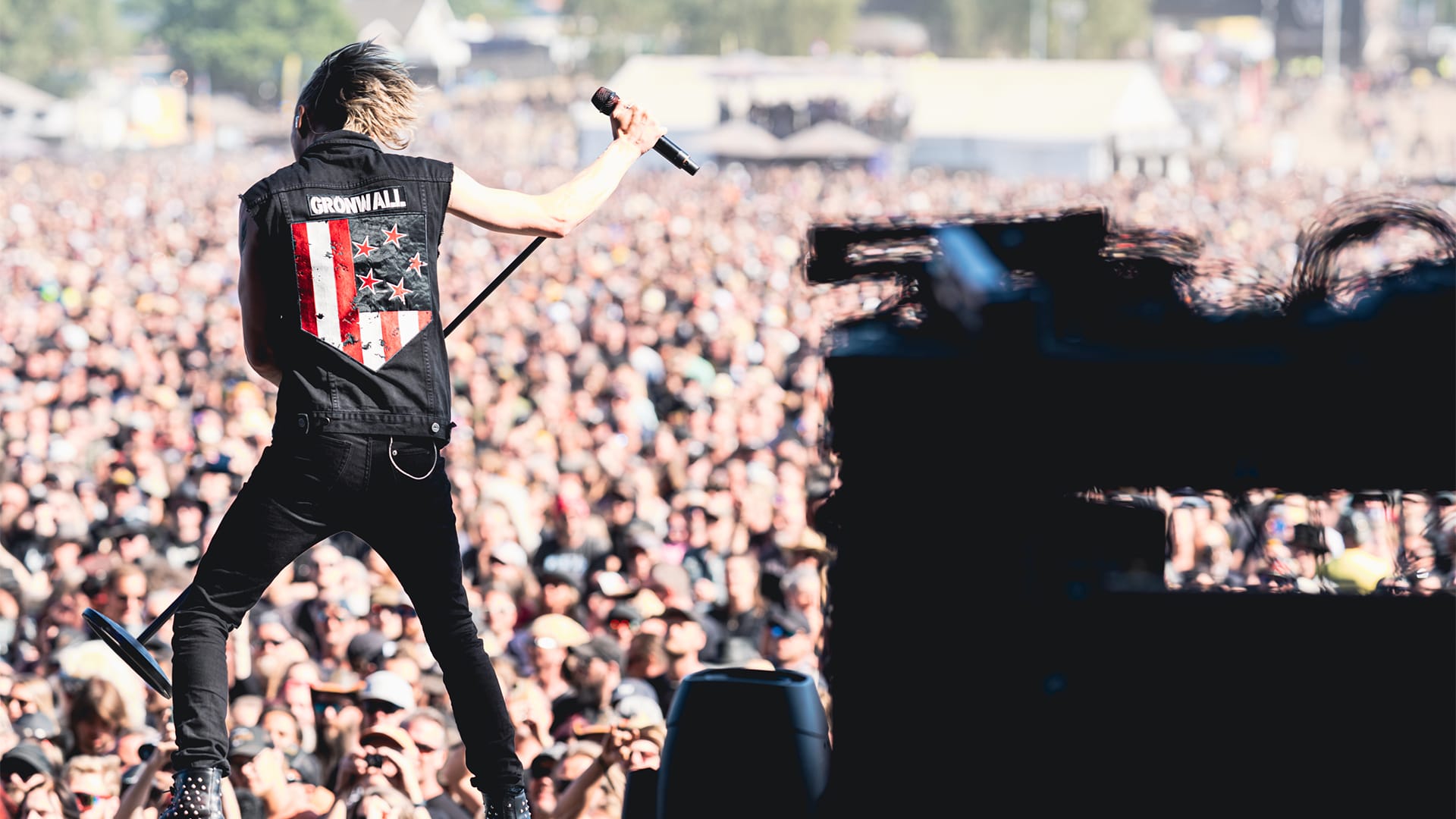 Erik står på scen med ryggen vänd mot kameran, i bakgrunden syns ett publikhav.