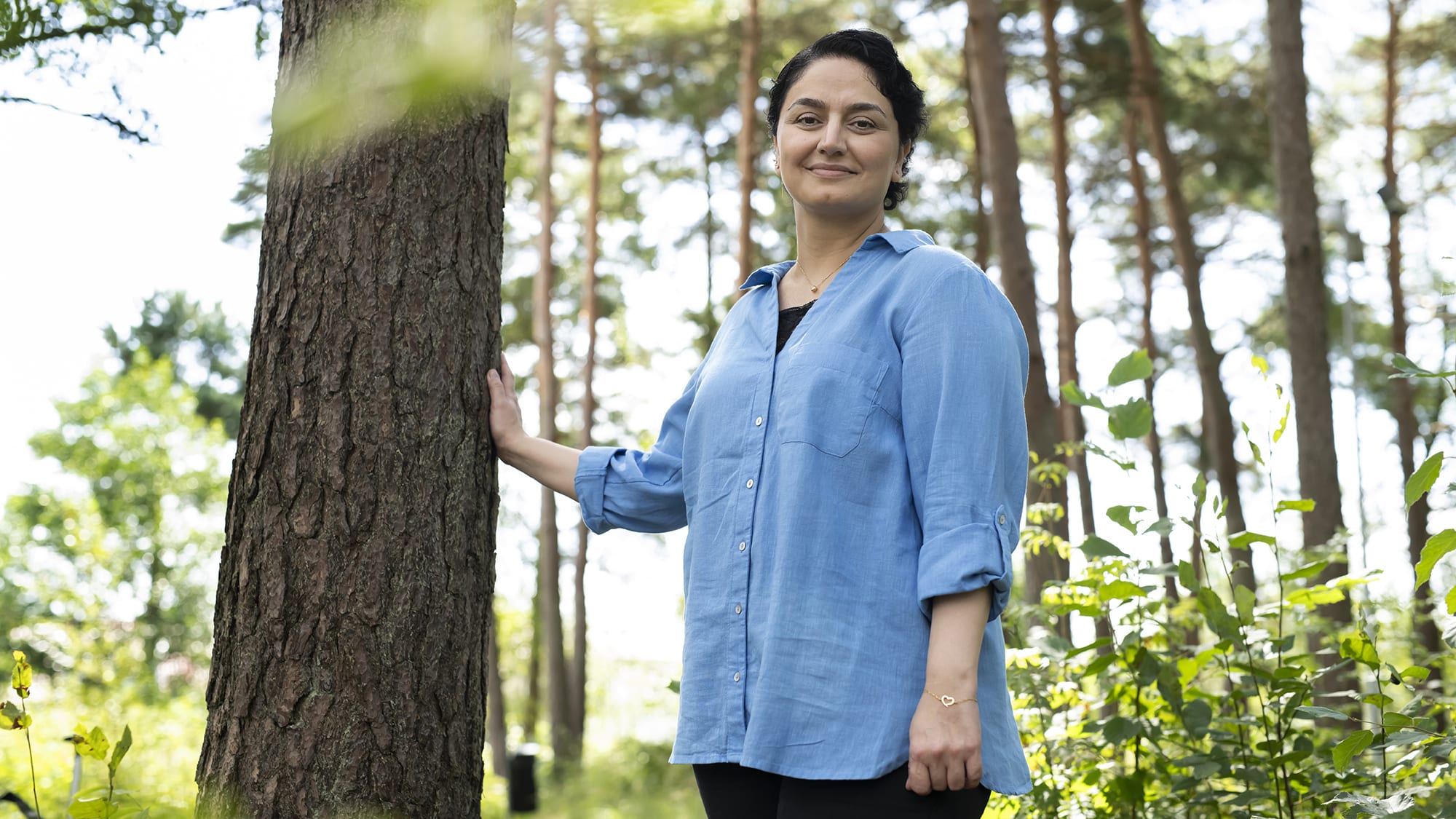 Neta lutar sig mot ett träd i skogen. Foto: Julia Sjöberg.