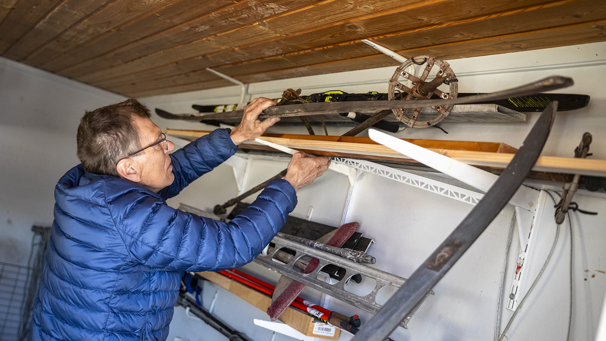 Man rotar bland gamla skidor i förrådet. Foto: Tobbe Nilsson.