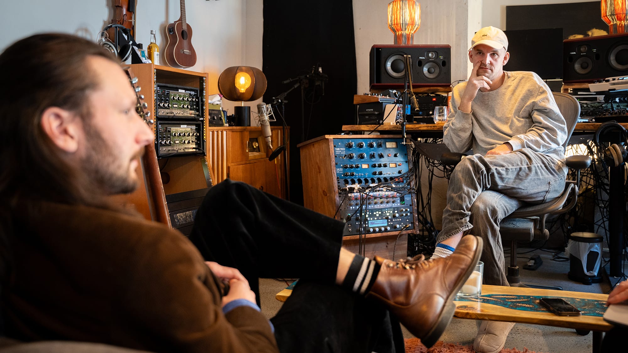 Två manliga, medelålders musiker sitter mitt emot varandra i en studio.