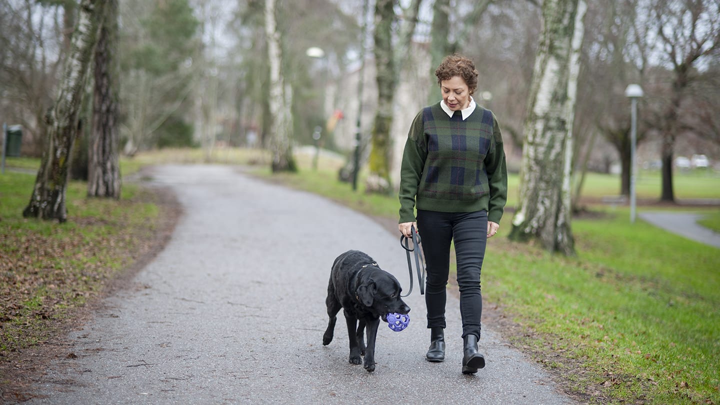 Kvinna går med hund i park