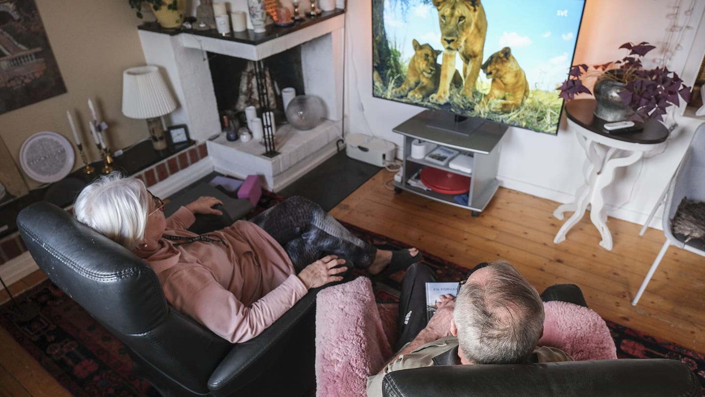 Par sitter i varsin fåtölj och tittar på tv