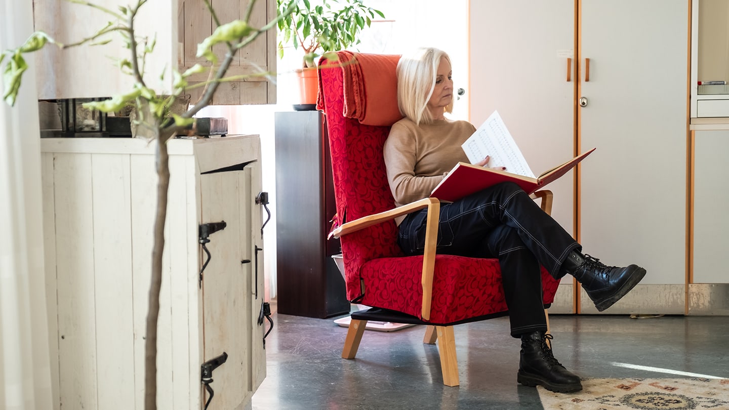 Kvinna sitter och läser bok på palliativ avdelning