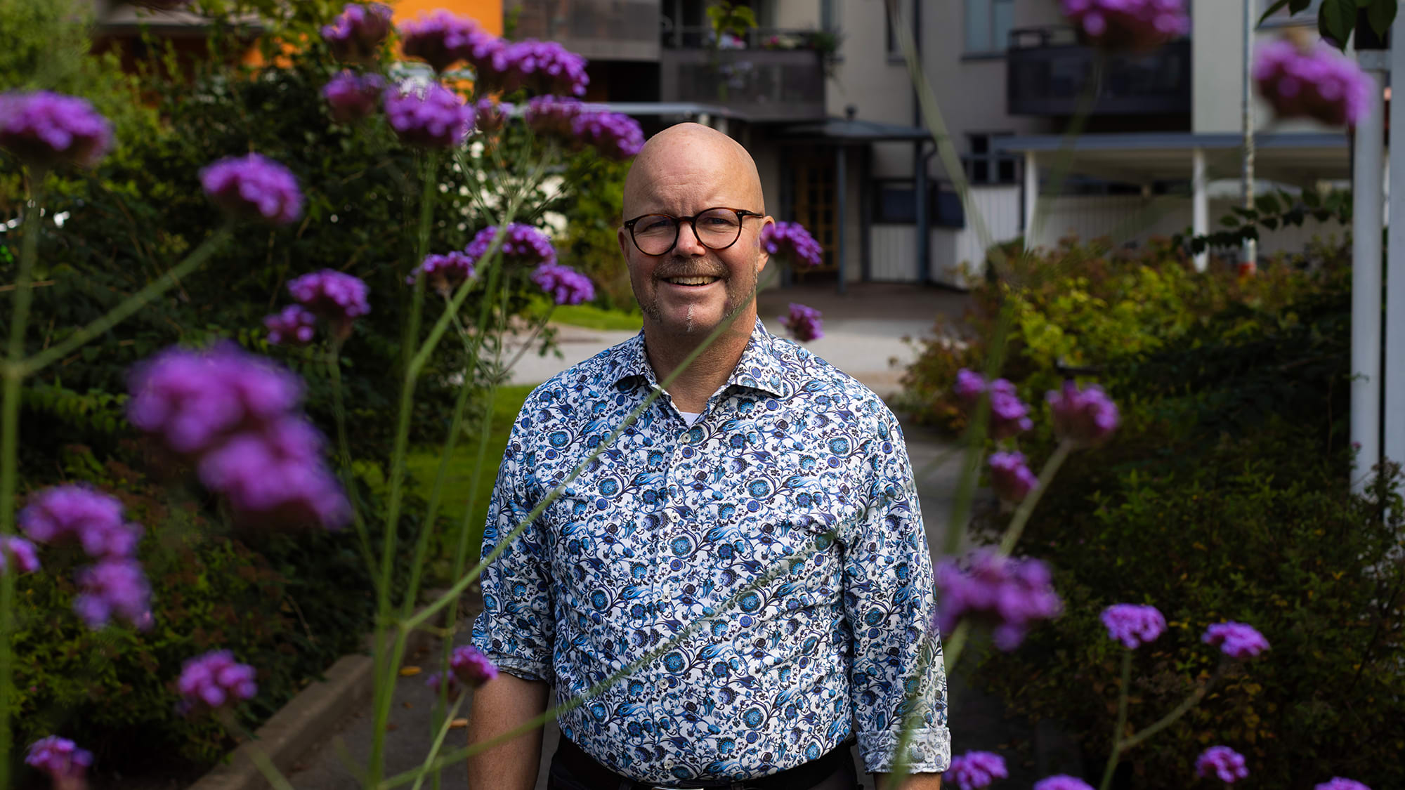 Medelålders man står bland blommor på en innergård.