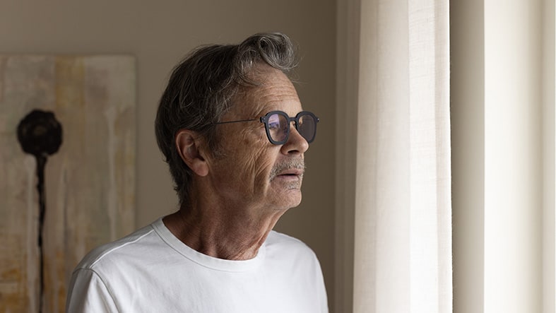 Man i profil tittar ut genom fönstret