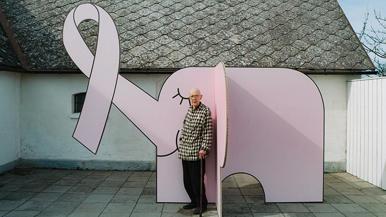 Äldre man framför rosa elefant