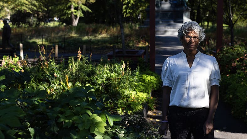 Medelålders kvinna med bakgrund i sydostasien vinna i trädgård