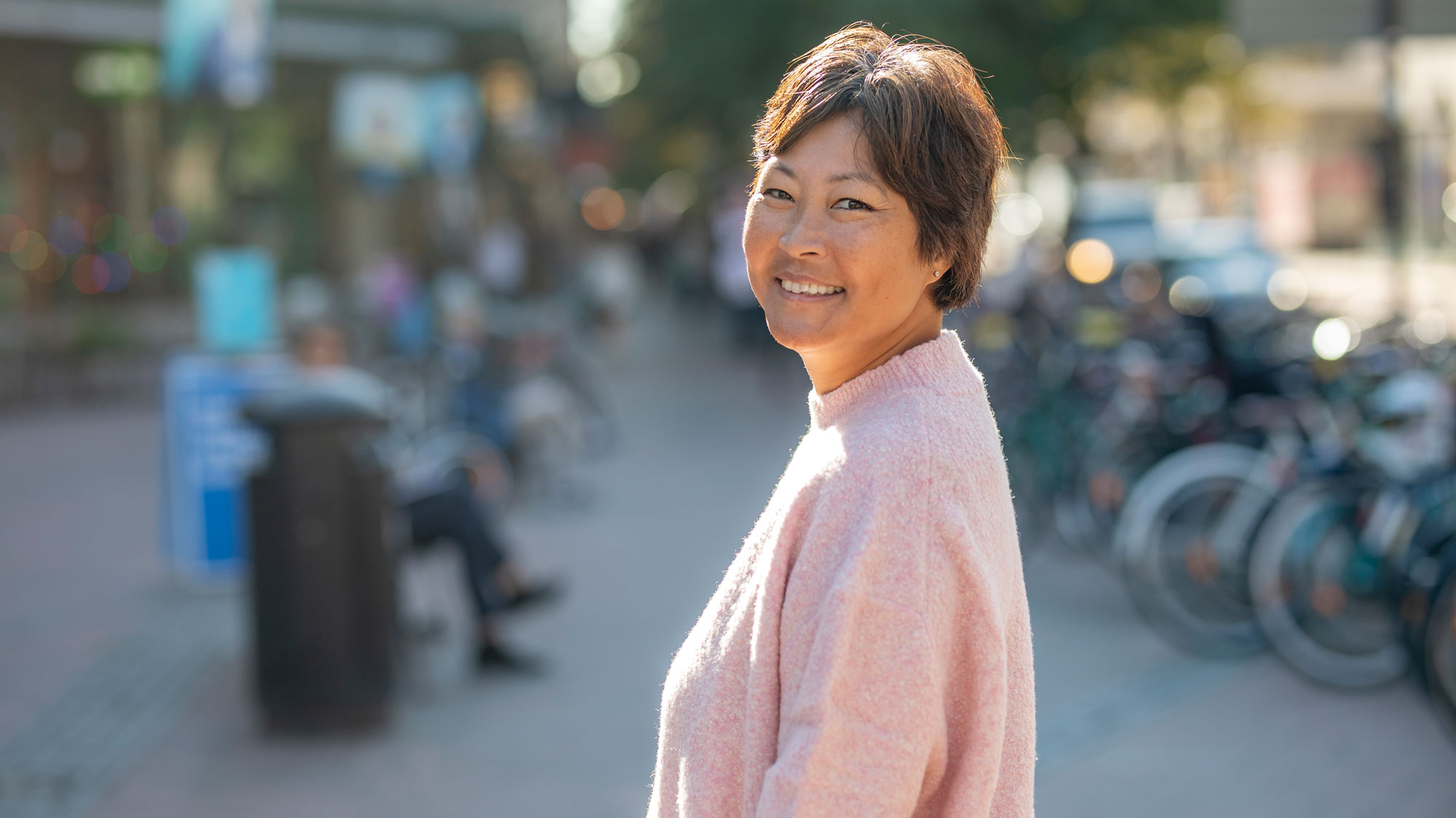 Helena Torsler Andersson, sjuksköterska på Cancerlinjen, står på ett en gågata i solen. 