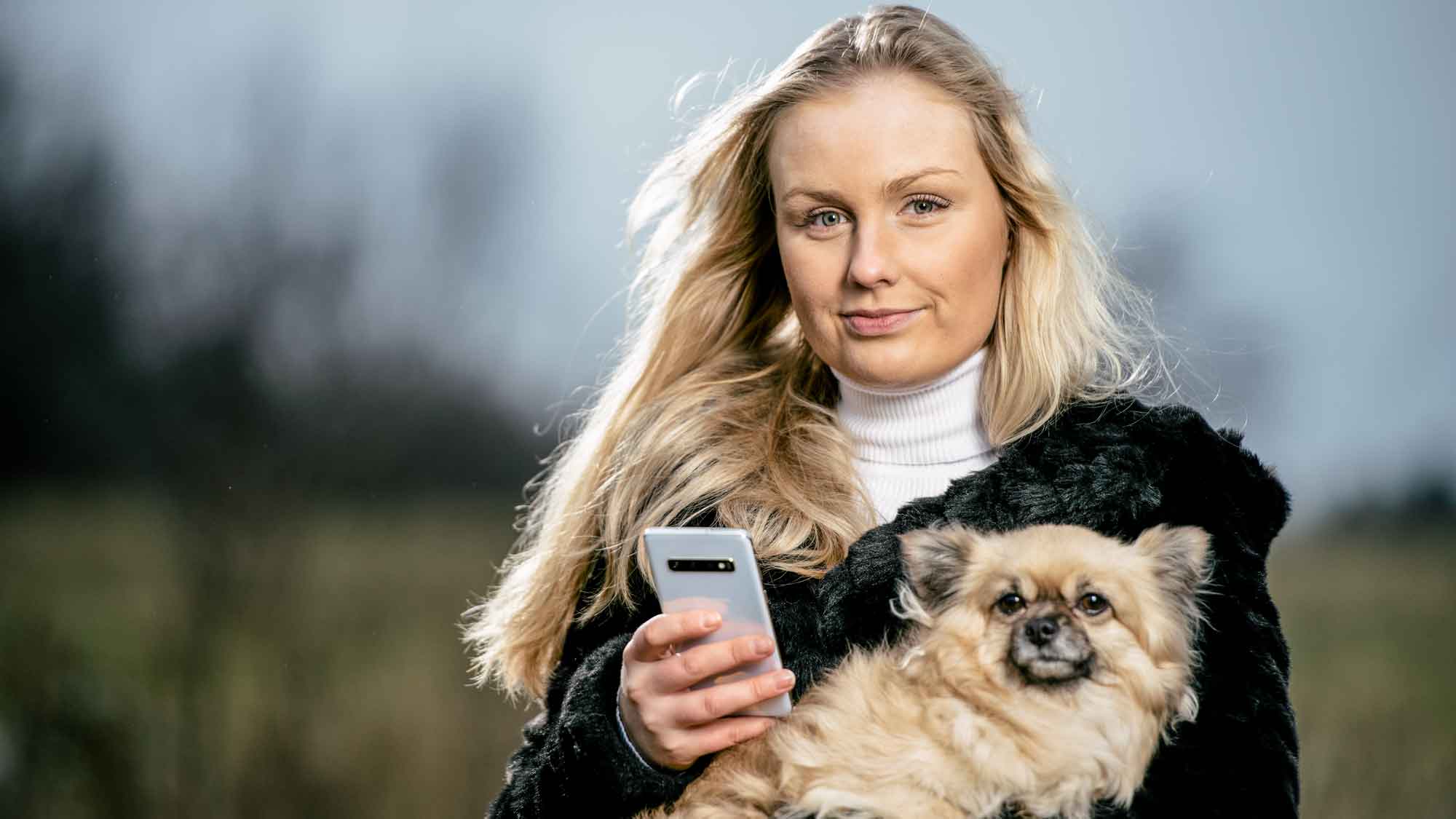 Cornelia Nilsson med sin hund och mobiltelefon