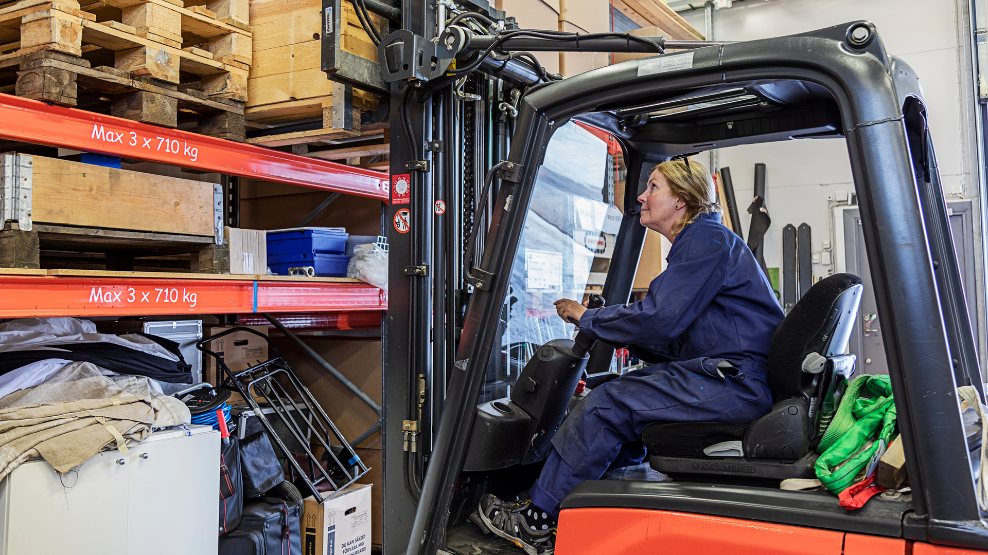 En kvinna kör en plocktruck på ett lager.