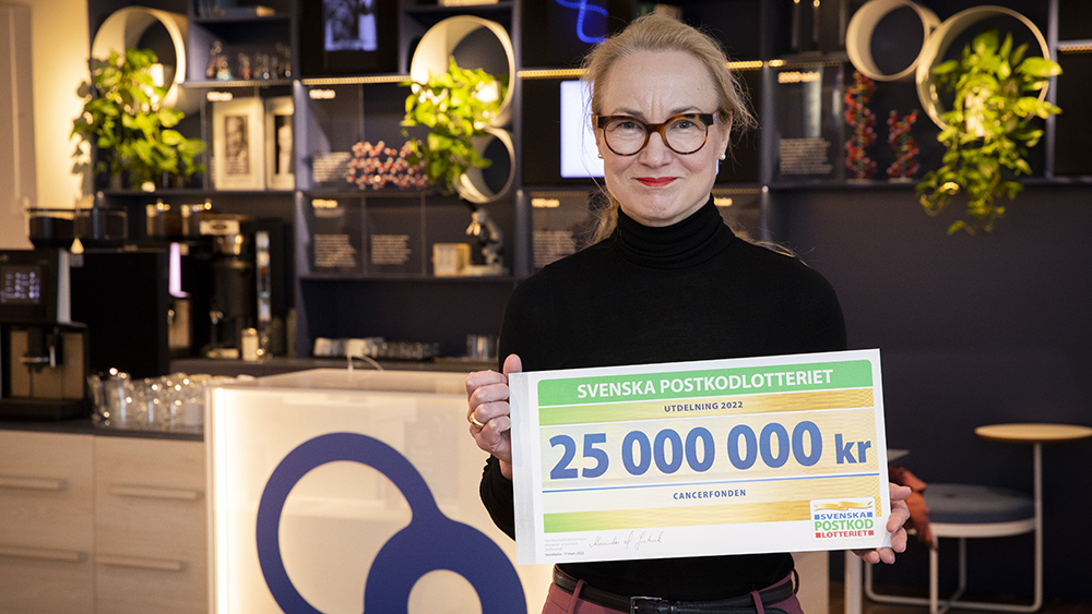 Cancerfondens generalsekreterare Ulrika Årehed Kågström med checken från Postkodlotteriet.