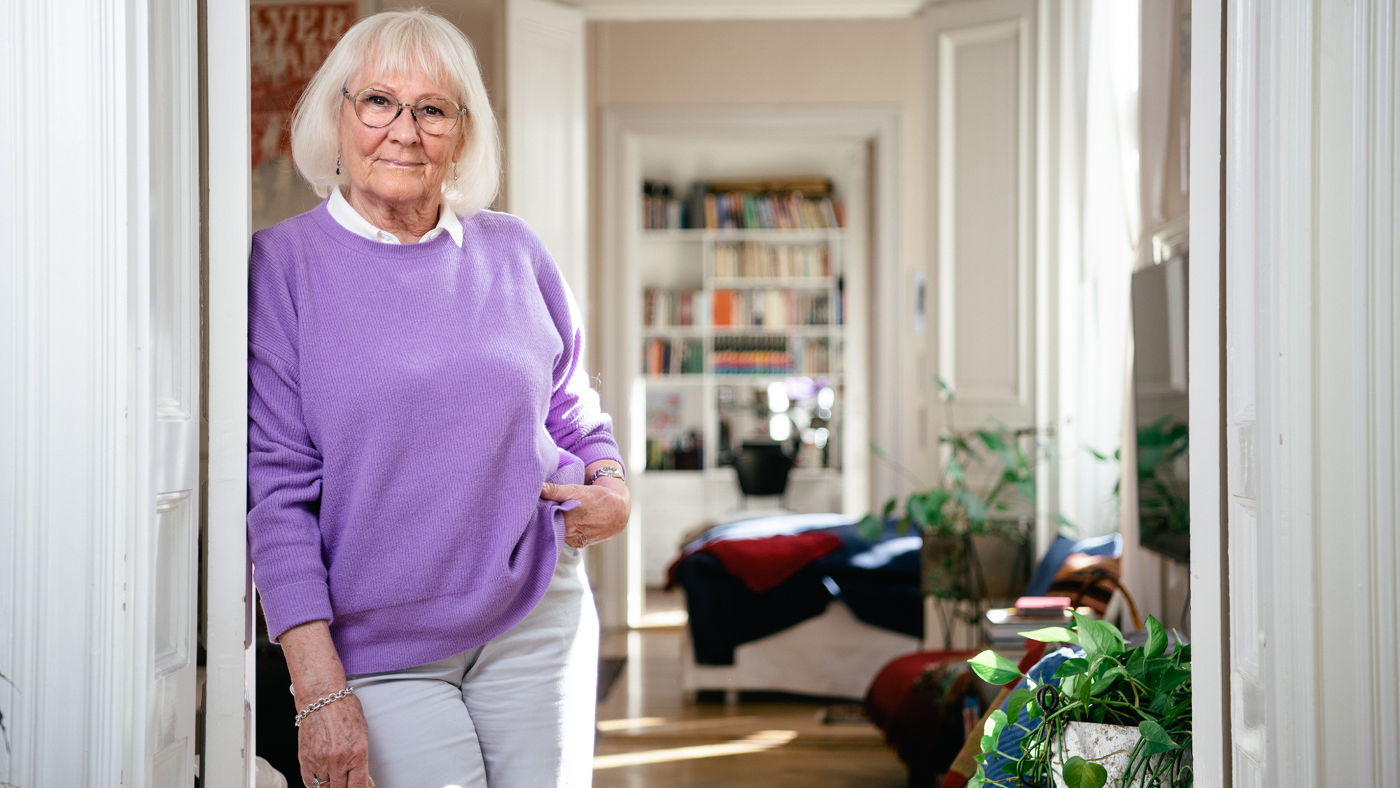 Inger Öst står lutad mot en dörrpost i sin lägenhet