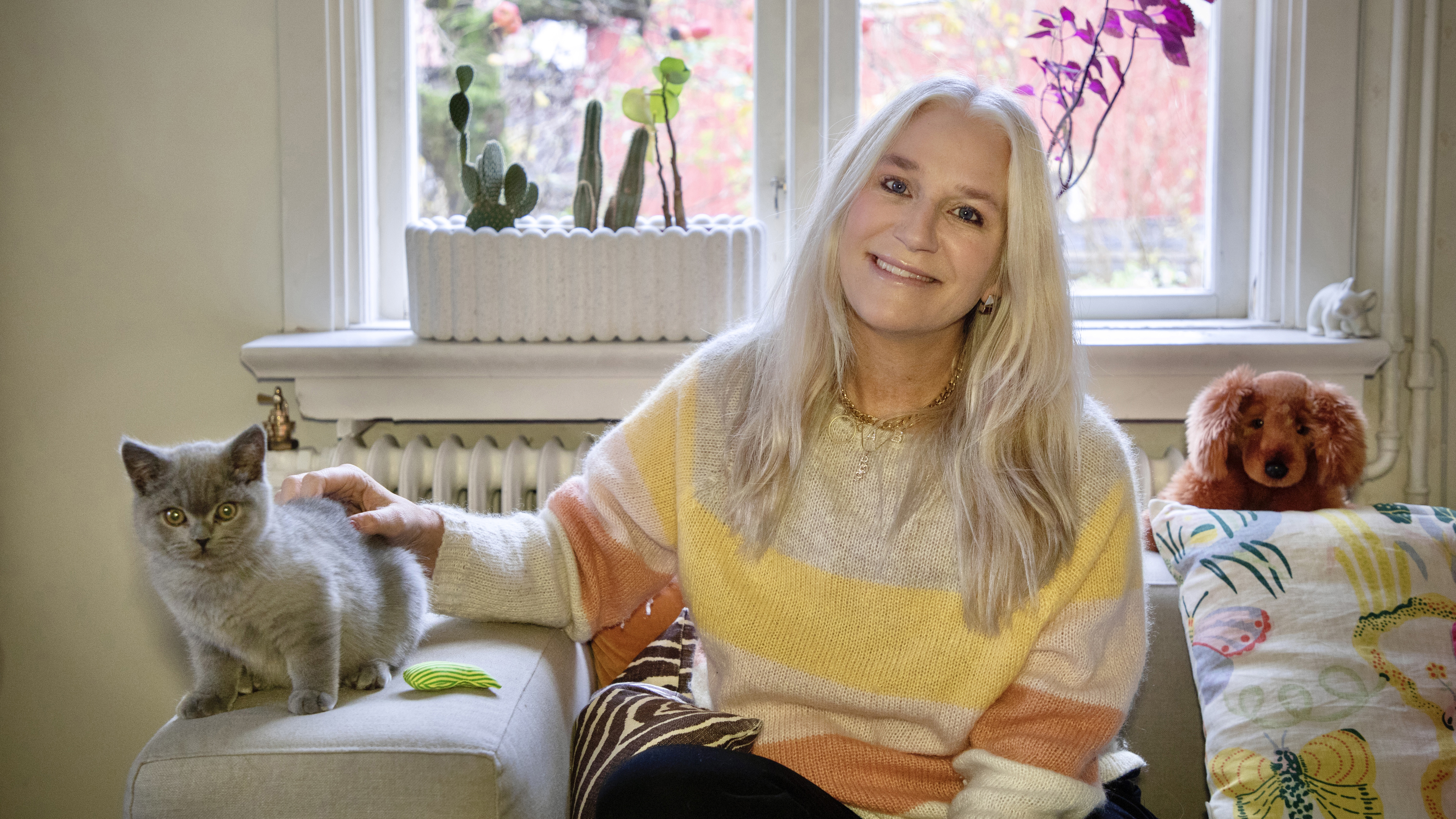 Ann Söderlund sitter i soffan tillsammans med kattungen Kattis.