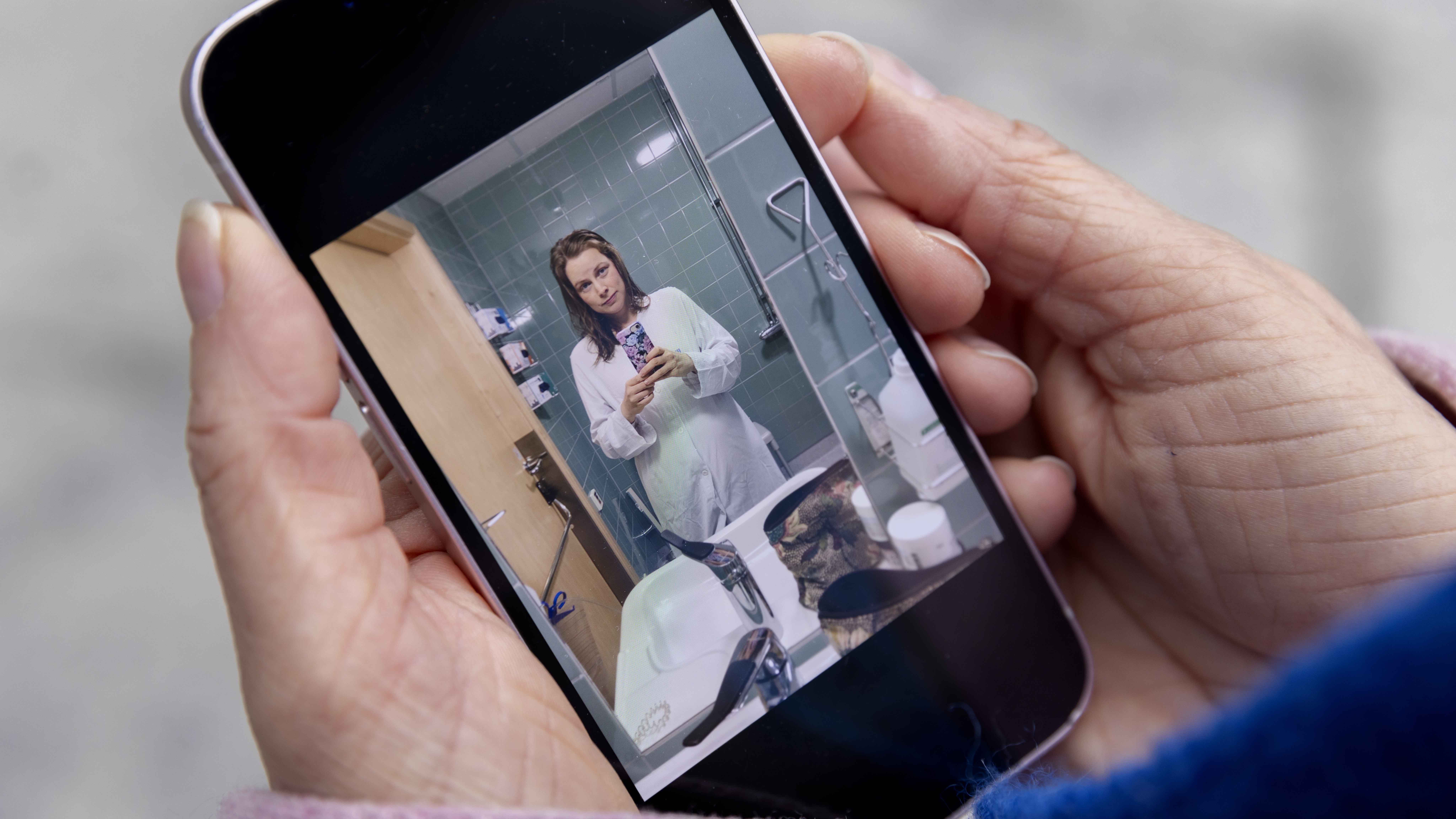 Kvinna i badrumsspegel på mobilen.