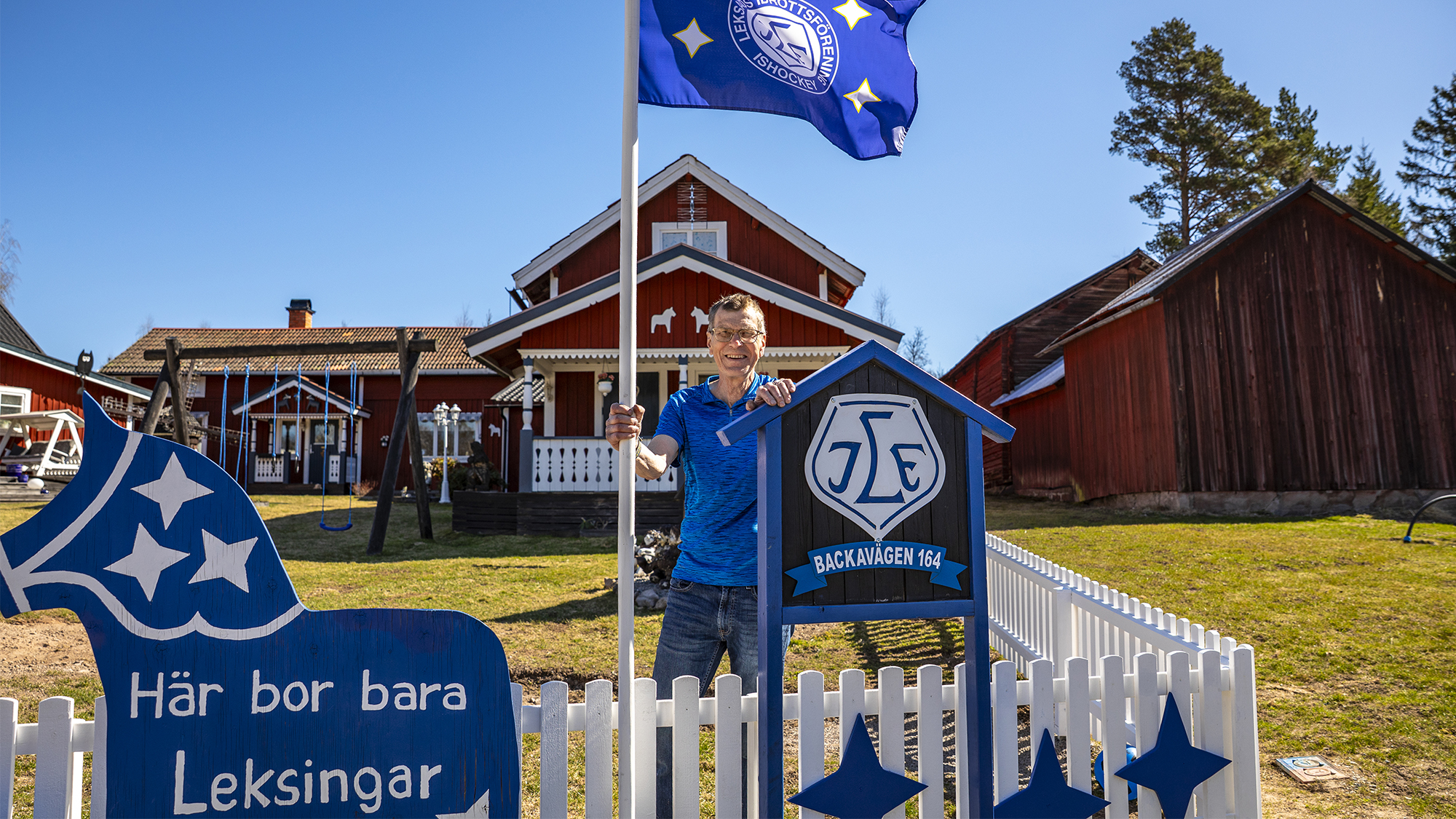 Anders Björkman framför sitt hus med Leksandflagga och skylt. Foto: Tobbe Nilsson.