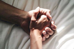Two people holding hands in bed
