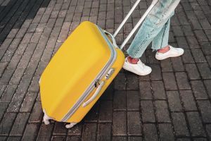 Person pulling yellow suitcase