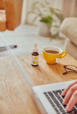 Cannaray CBD Oil next to tea & laptop