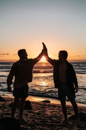 Men high fiving on beach