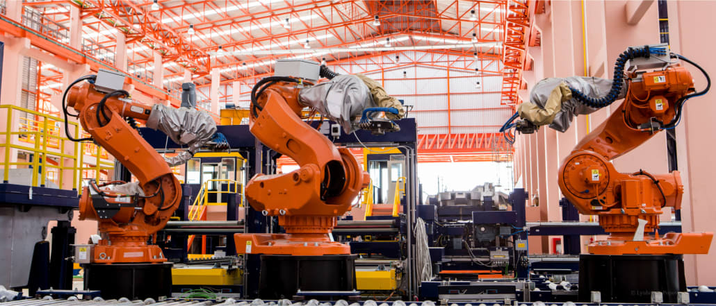 Three big robotic arms in a factory