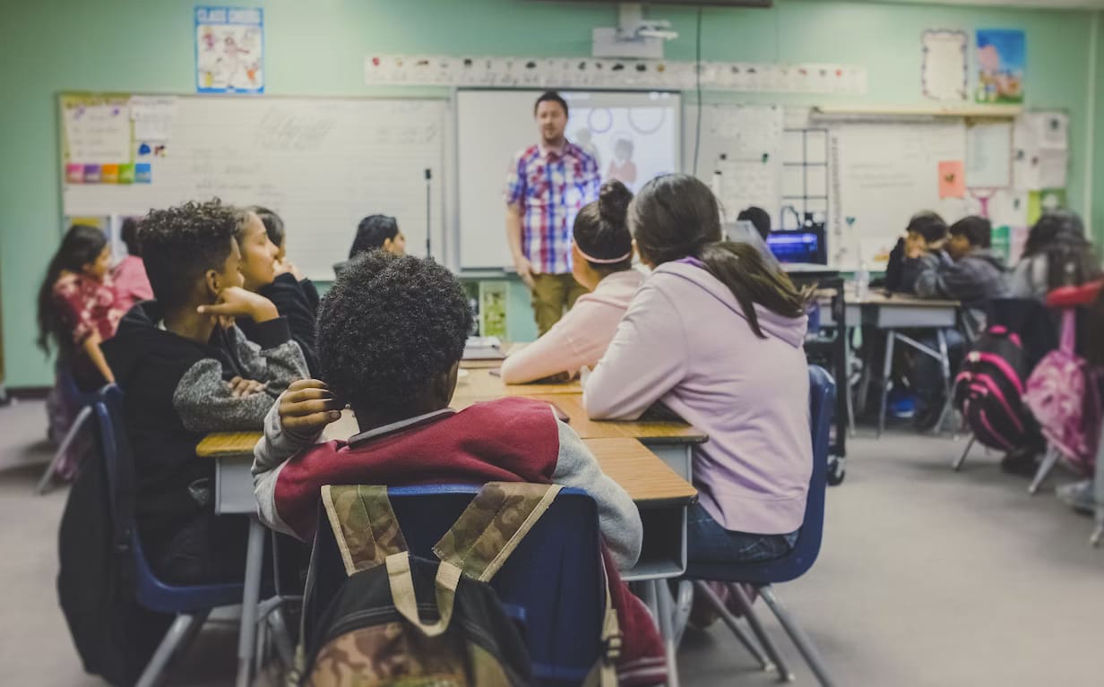 Children in a school classroom watching a teacher's presentation.