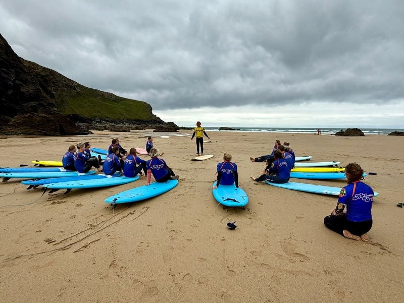people in black wetsuits participating in a surf less on a beach