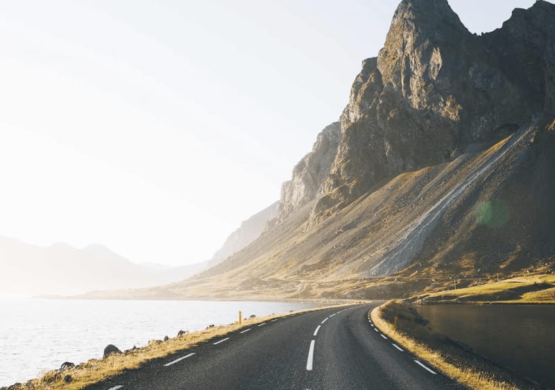 Image of a road in Iceland near mountains and the ocean.