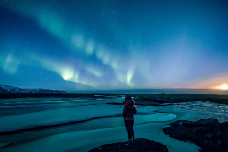 Image of a person standing and gazing at the Northern Lights in Iceland