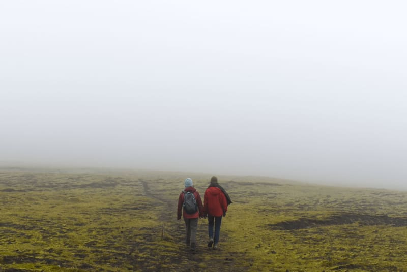 Image of two people hiking in the highlands of Iceland. Foggy weather.