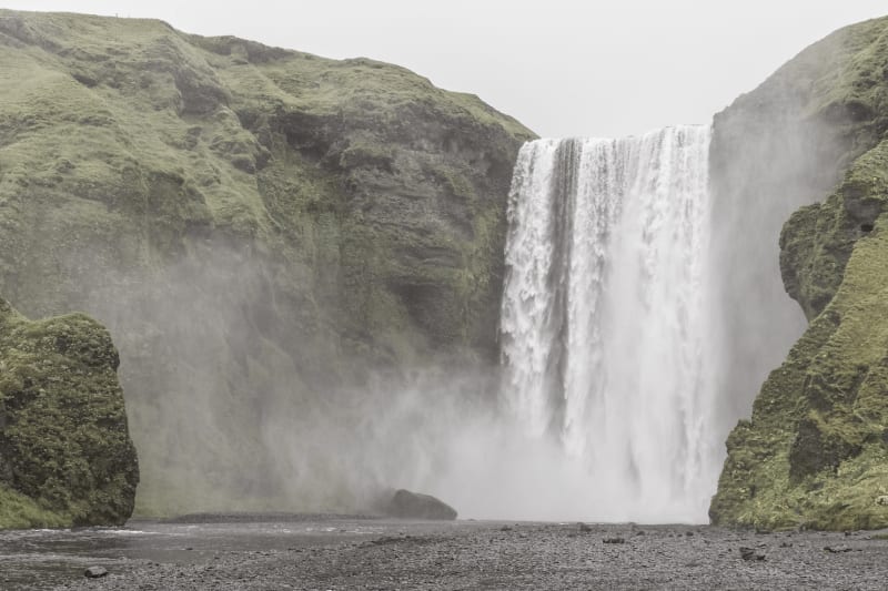 Image of a waterfall in Iceland, surrounded by green mountains.