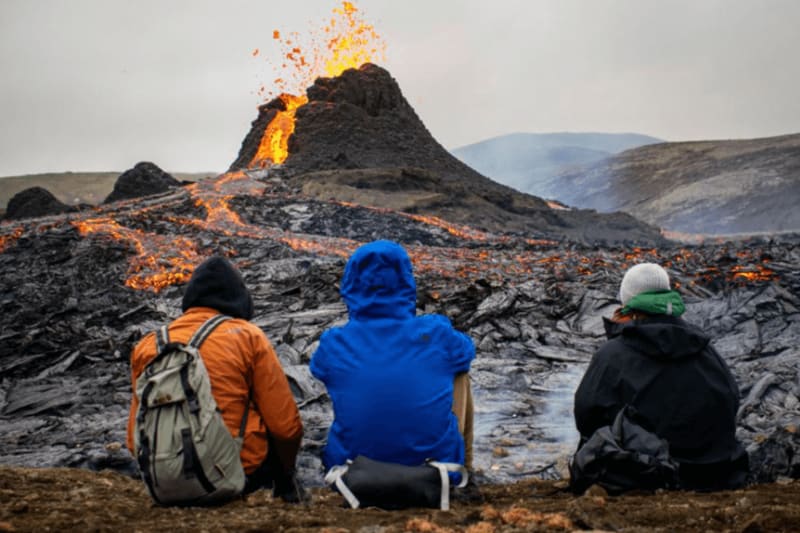 Image of people sitting in front of the volcano eruption.