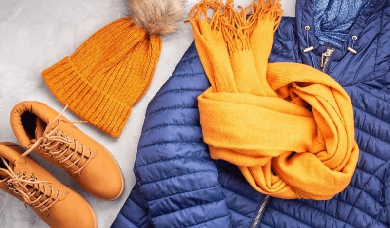Image of a warm hat, winter shoes, winter coat and a scarf for traveling in the cold in Iceland.