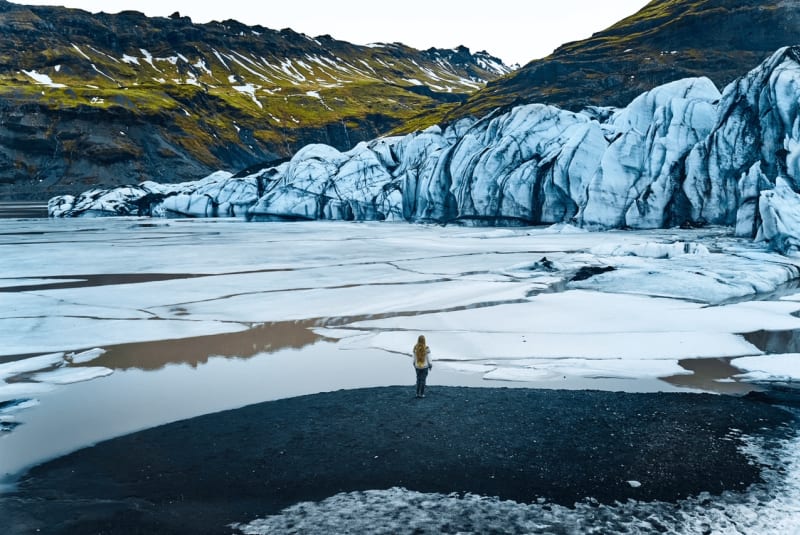 Image of people standing close to Solheimajokull (a glacier in Iceland)