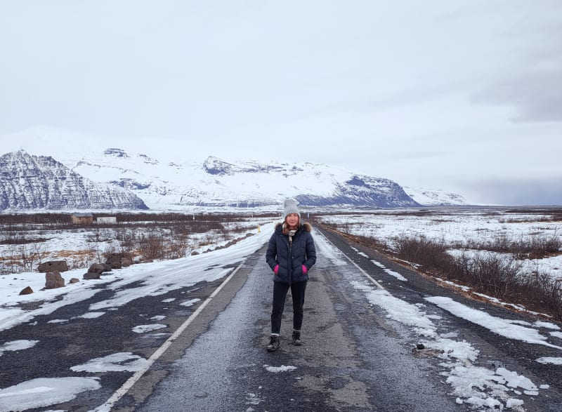 Image of a person standing in the middle of the snowy road in Iceland