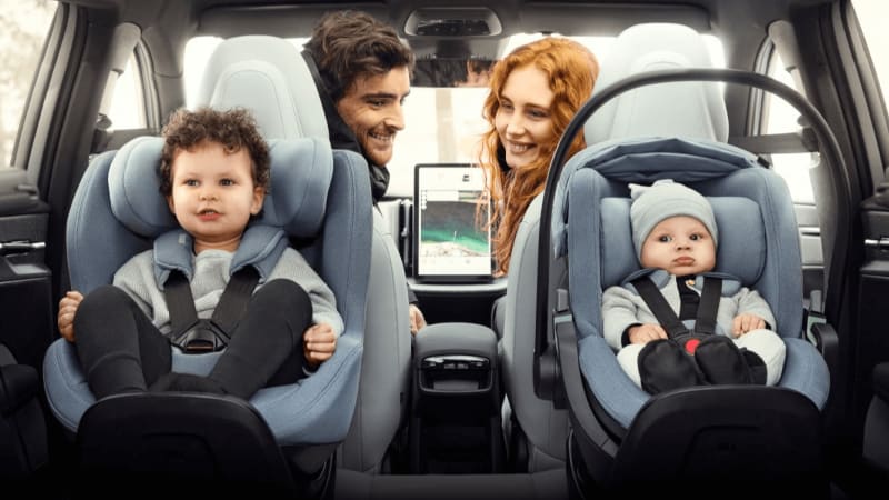 Image of two children sitting comfortably in a child seat with their parents in the front seat