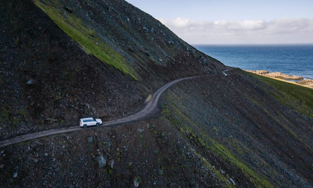 Image of a 4x4 driving on a ridge on rugged terrain in Iceland highlands.