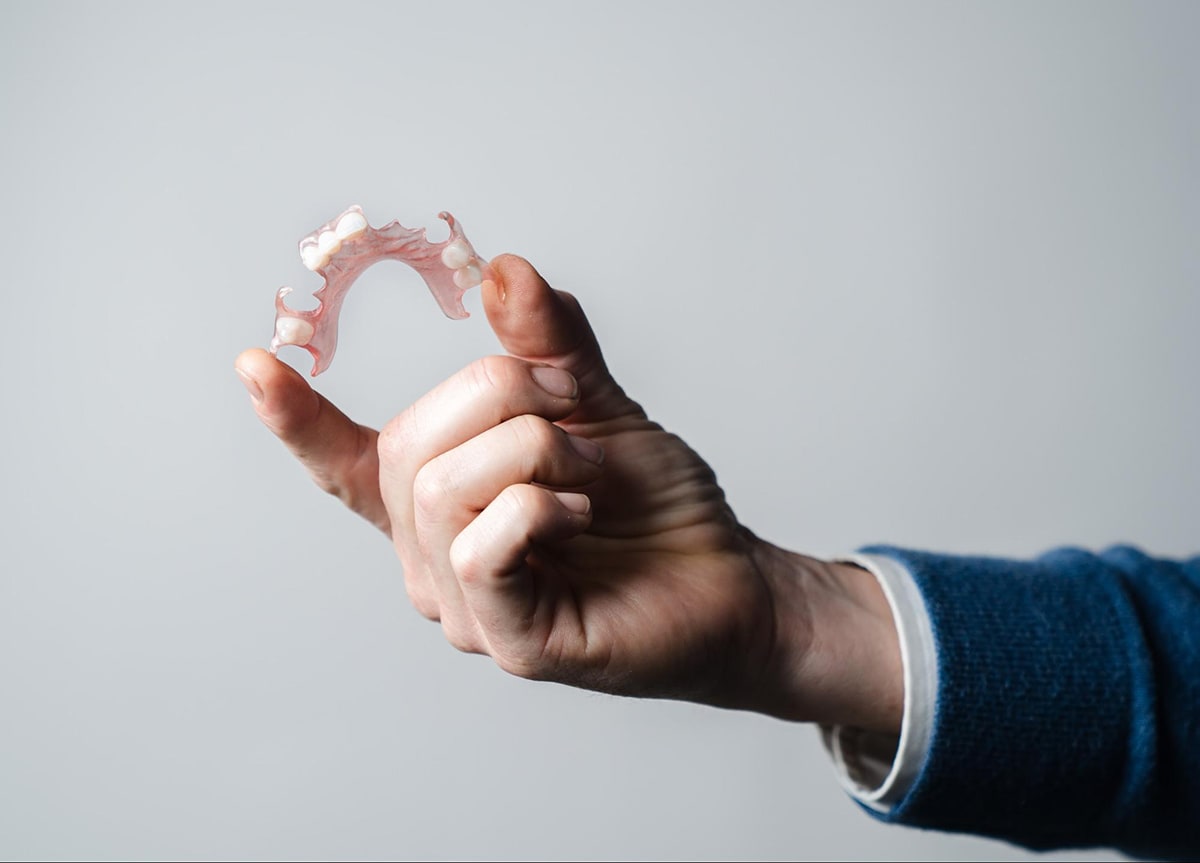 A man's hand holding an FP3D partial denture