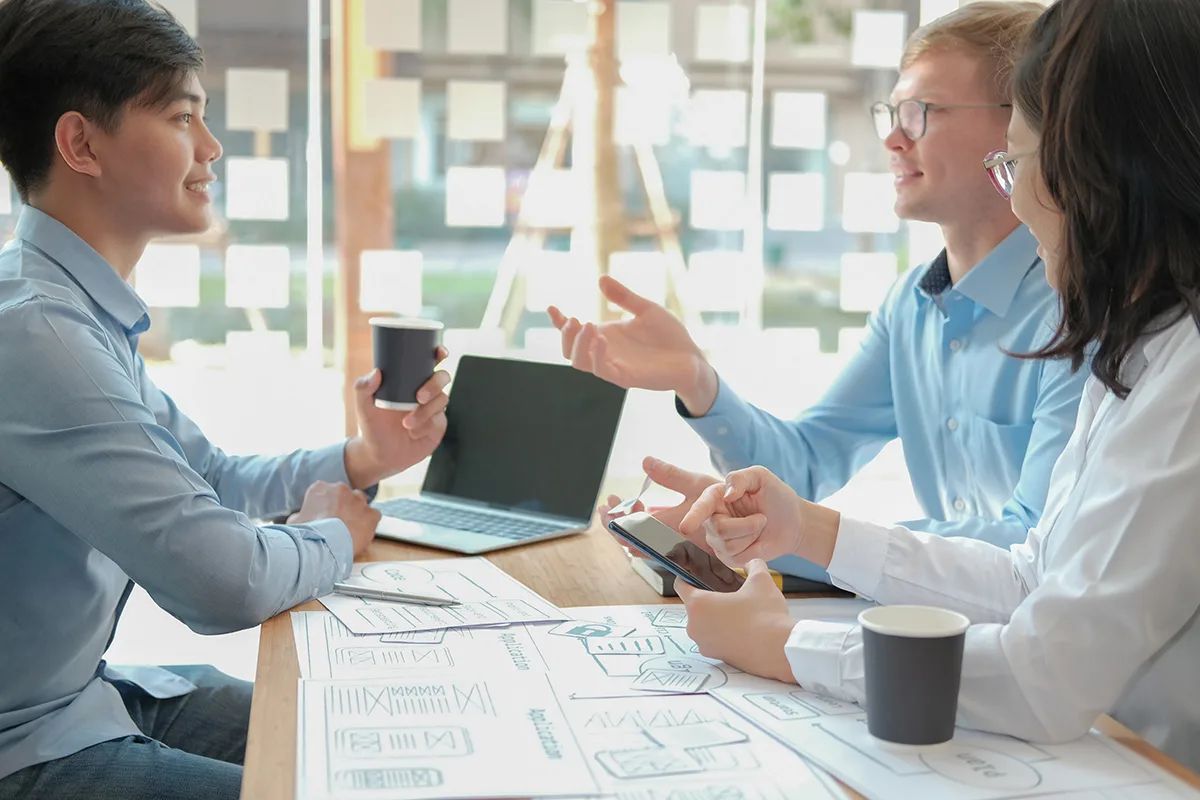 two men and a woman UI/UX designer discussing a project