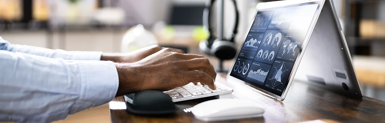 closeup shot of a couple of hands working on his keyboards with data graphs and charts showing on screen