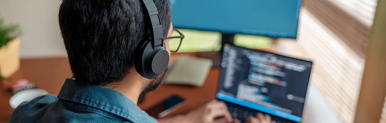 man on his laptop with headphones, attending a bootcamp online