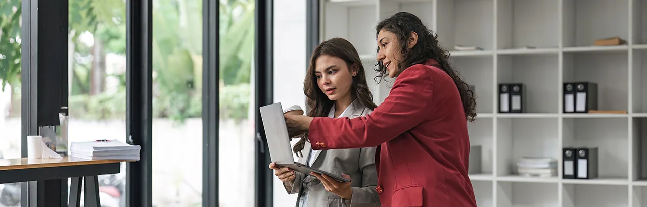 a couple of female cybersecurity analyst deep in discussion while looking at an open laptop